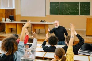 Students raising hands in a classroom.