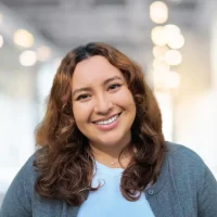 Smiling woman with curly brown hair in a professional office environment.