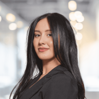 Confident woman with long black hair in a modern office setting.