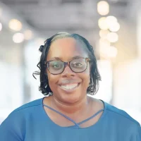 Professional woman wearing glasses smiling in an office setting.