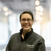 Professional woman wearing Canyon GBS branded jacket in a modern office setting.