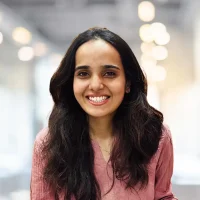 Smiling woman with long dark hair in a professional indoor environment, showcasing confidence and fr.