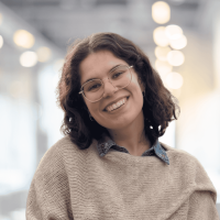 Young woman smiling in a modern office space with bright lighting and blurred background.