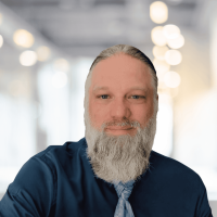 Professional portrait of a man with a beard in a modern office setting.